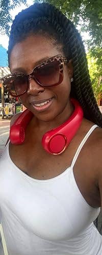Person wearing ample  sunglasses and a sleeveless top, with headphones astir   their neck, outdoors
