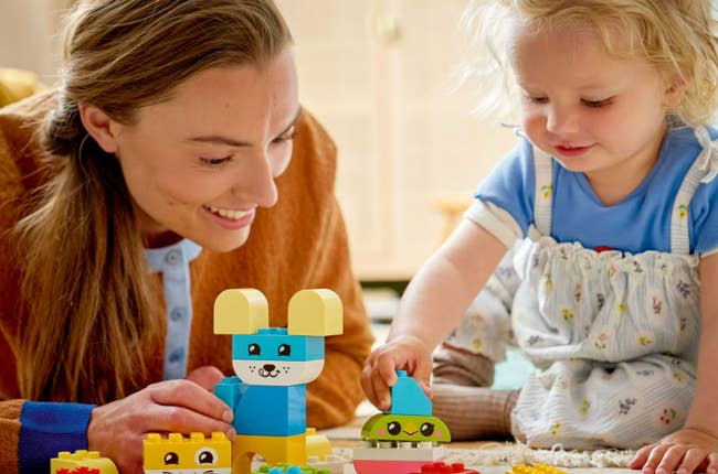 Adult and kid  happily playing with colorful gathering  blocks connected  a carpeted floor