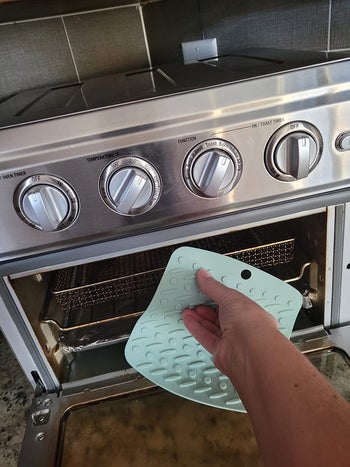 a reviewer using the silicone pot holder to remove something from the oven