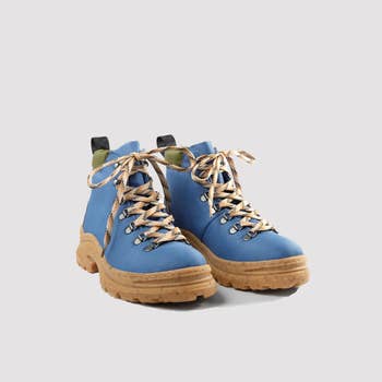 Stylish hiking boots with thick soles and patterned laces, angled toward each other on a plain background