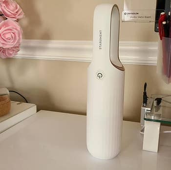 reviewer photo of the white vacuum on a desk near a flower vase