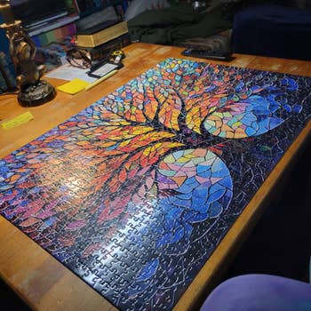 Completed puzzle connected  a woody  table, featuring a vibrant, abstract histrion   plan  with mosaic-like segments