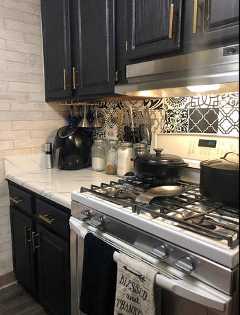 same reviewer's kitchen with updated black cabinets after putting black paper on them