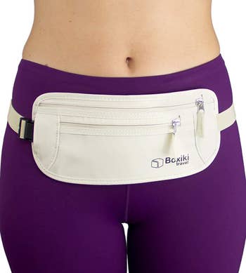 Person wearing a sleek, cream-colored waist pouch with aggregate  zippered compartments implicit    purple leggings, perfect  for question   organization