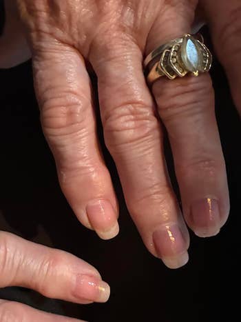 Close-up of manicured hands with a unsocial   golden  ringing  featuring a ample  stone, showcasing elegant nail grooming