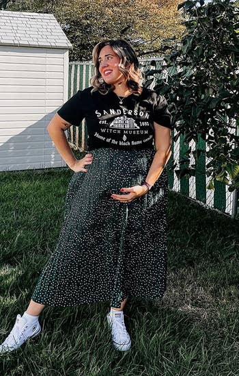 a reviewer showing their baby bump while wearing the green skirt