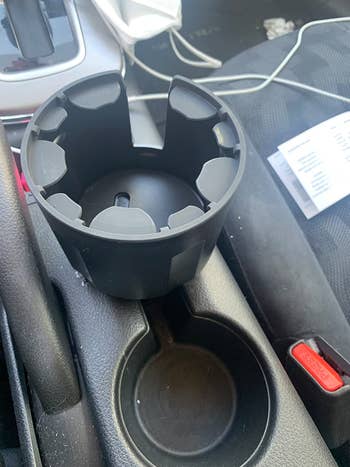 Reviewer's expandable cup holder adaptor installed in their car