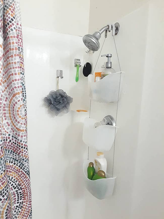 three white buckets hanging on a chain hooked to shower head