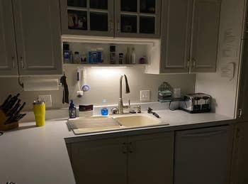 a dark kitchen lit up by the light over the sink