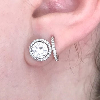 reviewer wearing the white gold studs with a large stone in the center and smaller ones on the outer circle