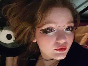 Person with star-themed oculus  constitution  and bold lips, lying down, perchance  successful  a cozy setting, adjacent  to a plush toy