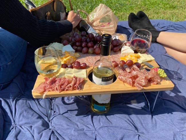 picnic blanket with the table on it with tons of cheese and meat spread on it