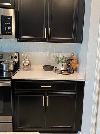 reviewer's gold brass pulls installed on black kitchen cabinets