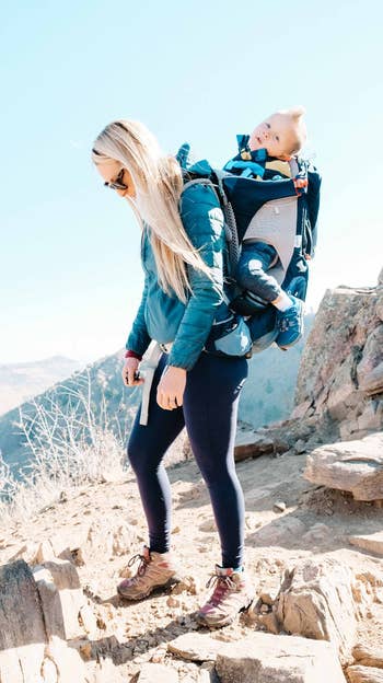 woman wearing Merrell hiking boots, wearing baby on her back