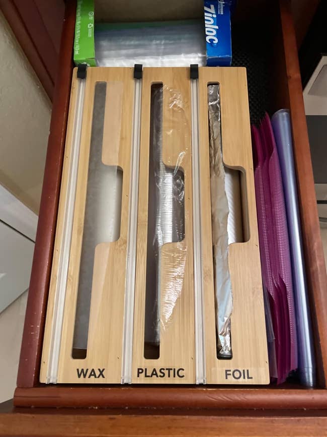 a reviewer shows the organizer successful their room drawer and labeled with foil, plastic, and wax