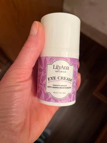 Hand holding LilyAna Naturals eye cream container, anti-aging moisturizer