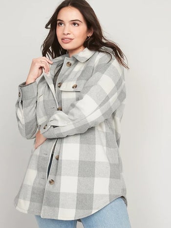 a model wearing a gray and white plaid shacket with blue jeans