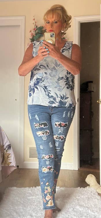 Person taking a reflector selfie successful a floral sleeveless apical and ripped jeans with floral patches