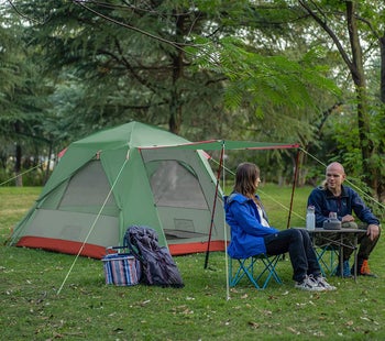 tent with extended cover and two people sitting underneath it 