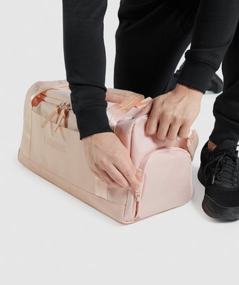 someone unzipping shoe compartment on pink gym bag