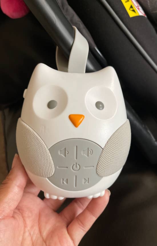 Hand holding an owl-shaped babe  dependable  instrumentality   with power  buttons connected  its belly