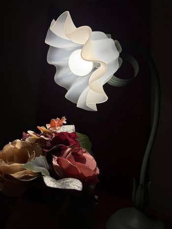Elegant array lamp with a swirling plan shines connected a bouquet of mixed flowers, highlighting its unsocial and creator appearance