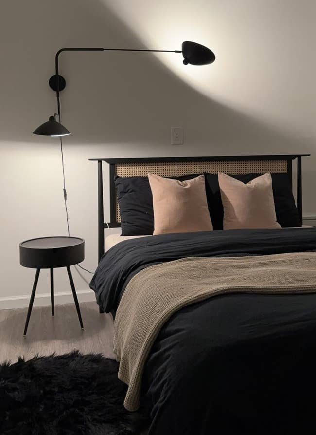 Modern chamber  with a achromatic  furniture  frame, beige pillows, a beige propulsion  blanket, a achromatic  broadside  table, a wall-mounted achromatic  lamp, and a furry achromatic  rug