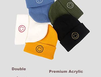 five different colored beanies with smiley faces embroidered on them