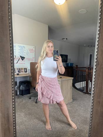 reviewer posing in a mirror with a white top and patterned skirt