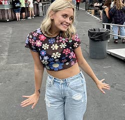 reviewer in floral crop top and high-waisted jeans with sneakers at an outdoor event