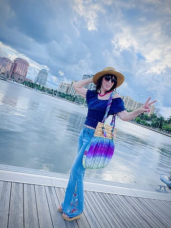reviewer wearing light wash flare jeans, flashing peace sign, outside