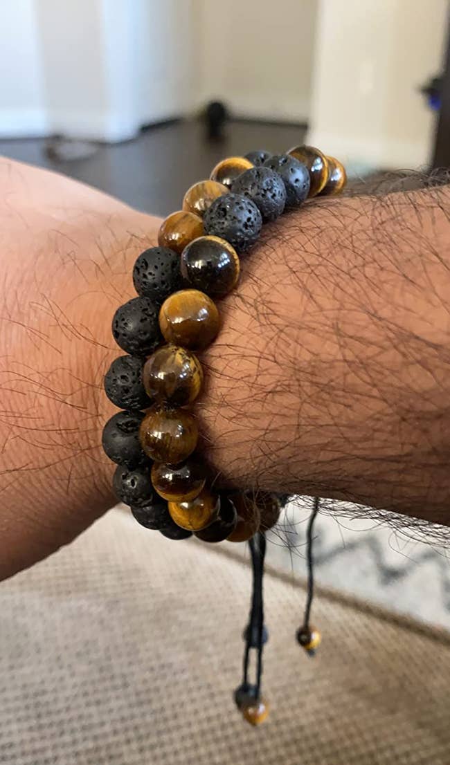 Reviewer image of two black and tiger eye beaded bracelets with string size adjuster