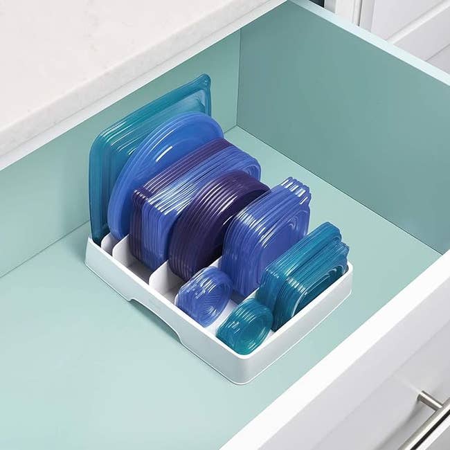Plastic nutrient retention lids neatly organized successful a drawer utilizing a achromatic divider holder