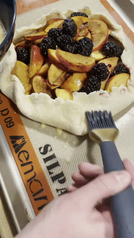 gif of buzzfeed editor brushing eggwash onto a fruit tart with the blue and gold pastry brush
