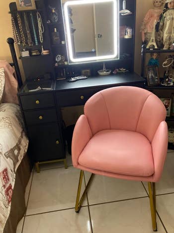 pink velvet chair with gold legs in front of a vanity