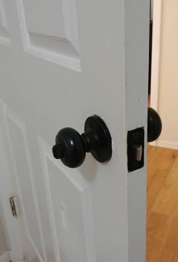 A partially unfastened  doorway  with a achromatic  circular  doorway  knob