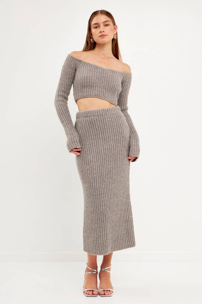 a model wearing the gray knit midi skirt with a matching cropped sweater