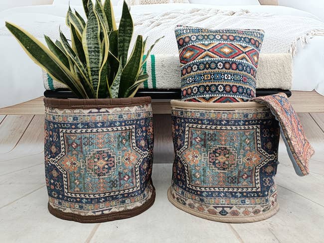 Two decorative plant pots with traditional patterns, one housing a snake plant, in a cozy room setting
