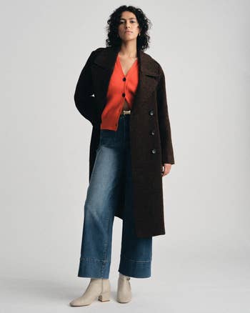 Person modeling a agelong overgarment implicit a cardigan, wide-leg jeans, and ankle boots, successful a fashion-forward style