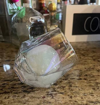 reviewer's iridescent glass on it's side with a large ice ball in it