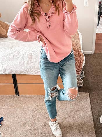 reviewer wearing pink henley sweater with ruffles at the collar and cuffs with jeans
