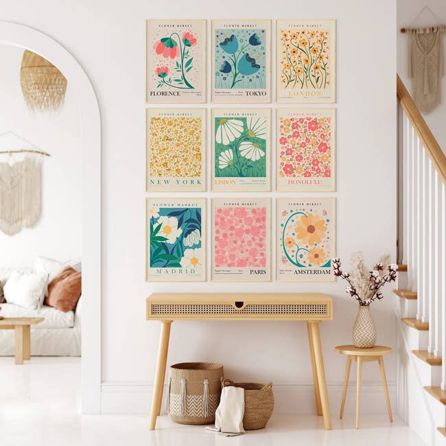 watercolor pastel prints of flowers from nine different cities in frames on a wall 