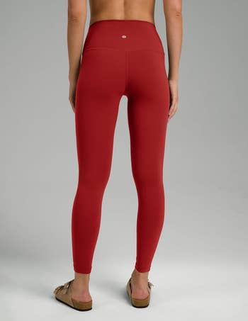 Person wearing reddish  high-waisted leggings and casual sandals, viewed from the back