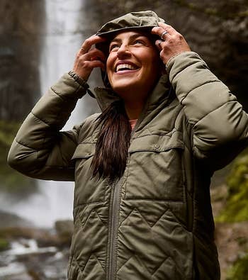 a model wearing a green quilted jacket with the hood up 