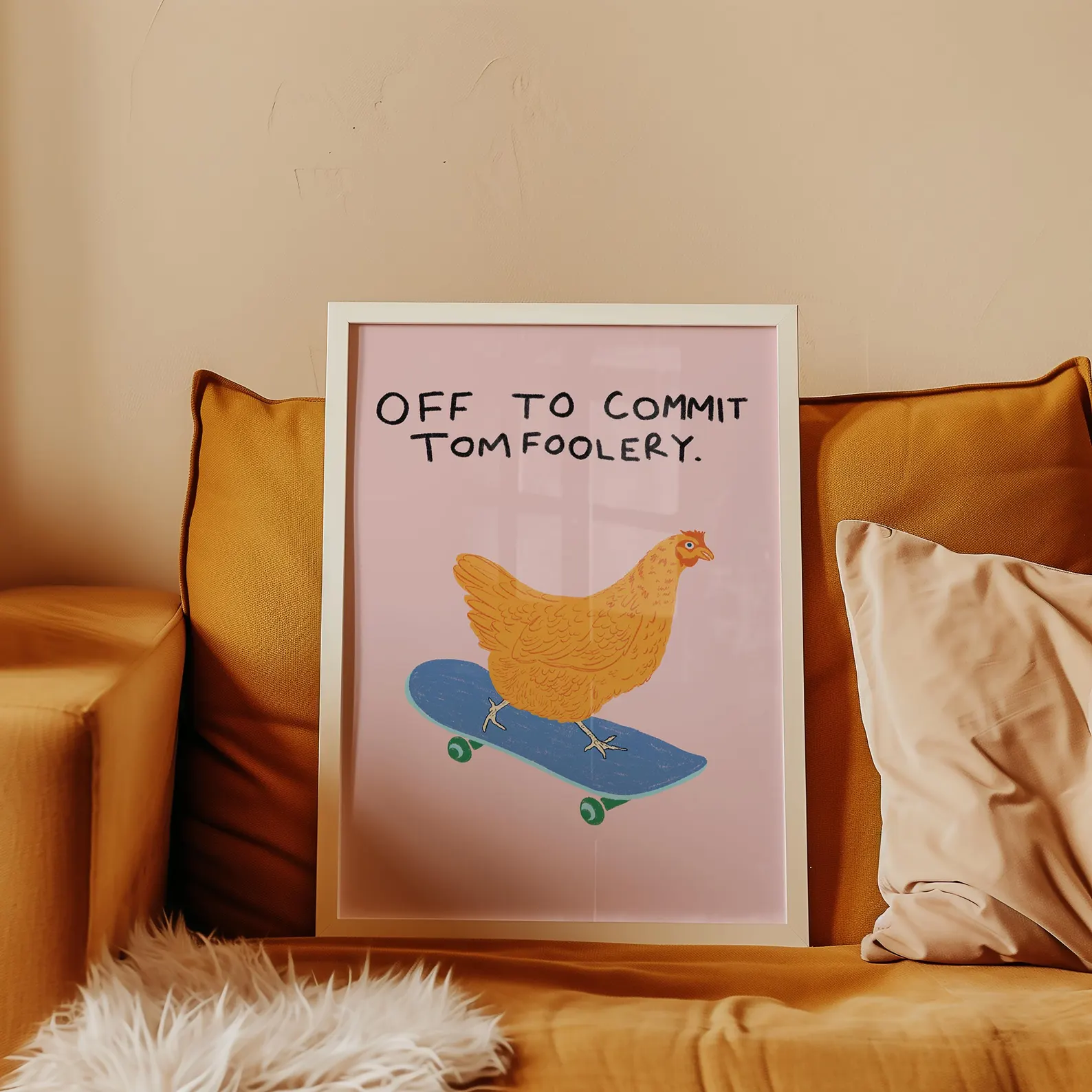 Framed poster on a couch showing a chicken riding a skateboard with the text: 