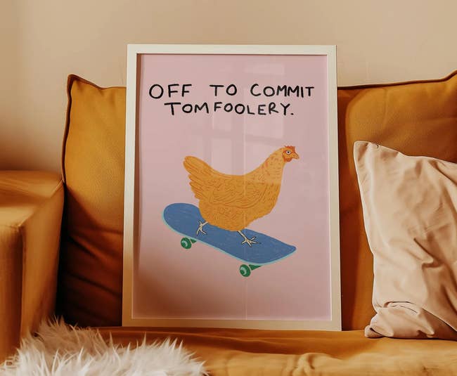Framed poster on a couch showing a chicken riding a skateboard with the text: