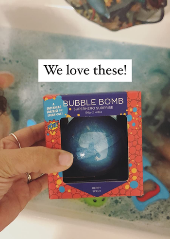 reviewer photo of a blue bath bomb in a box above a bath 
