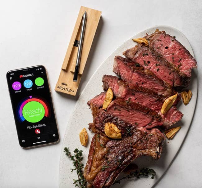 Meat thermometer next to a cut up steak and an app showing the internal temp 