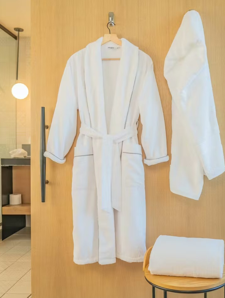 a white bath robe hanging up in a bathroom 