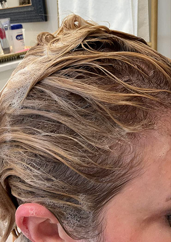 Reviewer with lather of shampoo worked in to their hair